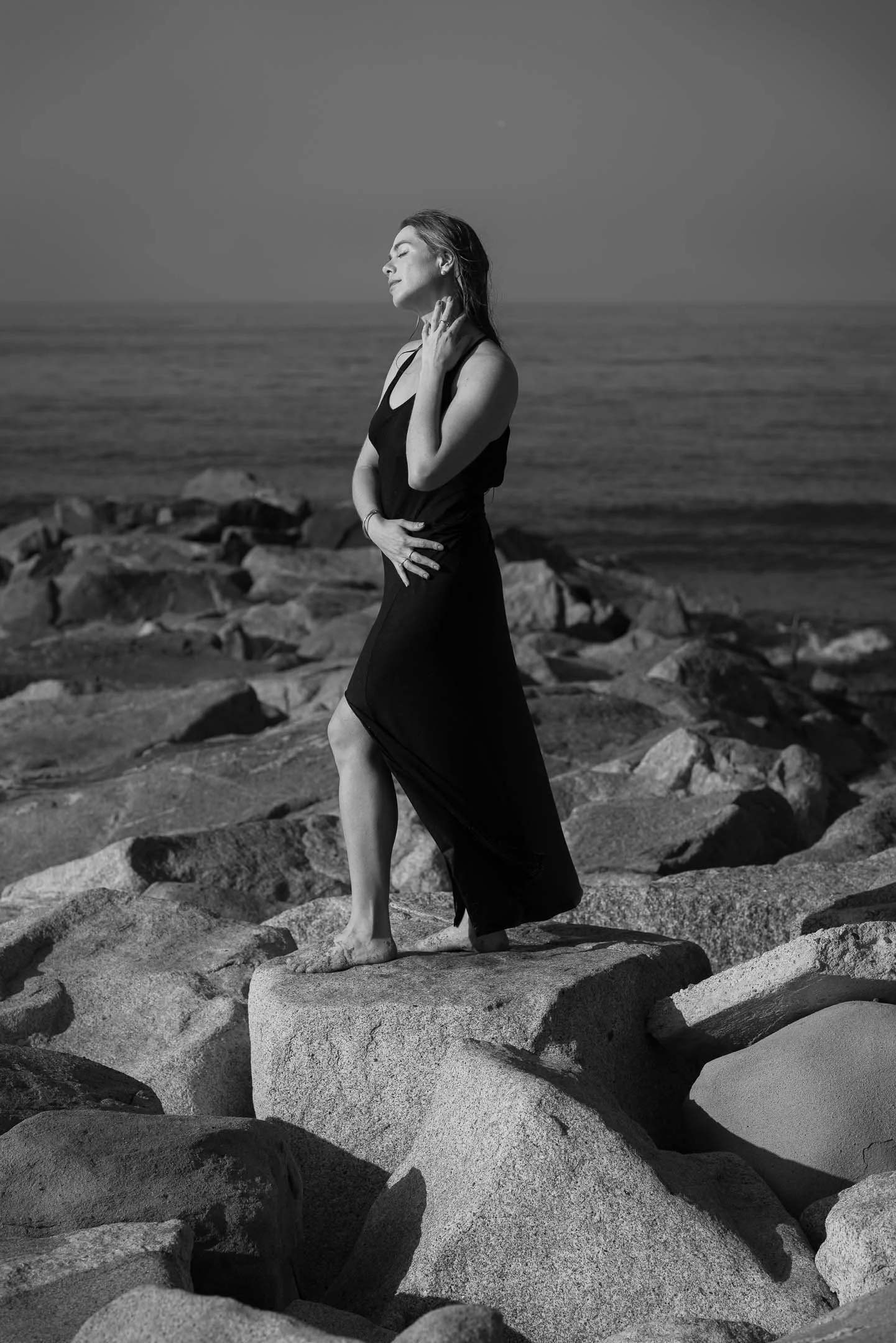 Black and white image of model posing on the rocks at the beach in Santa Monica