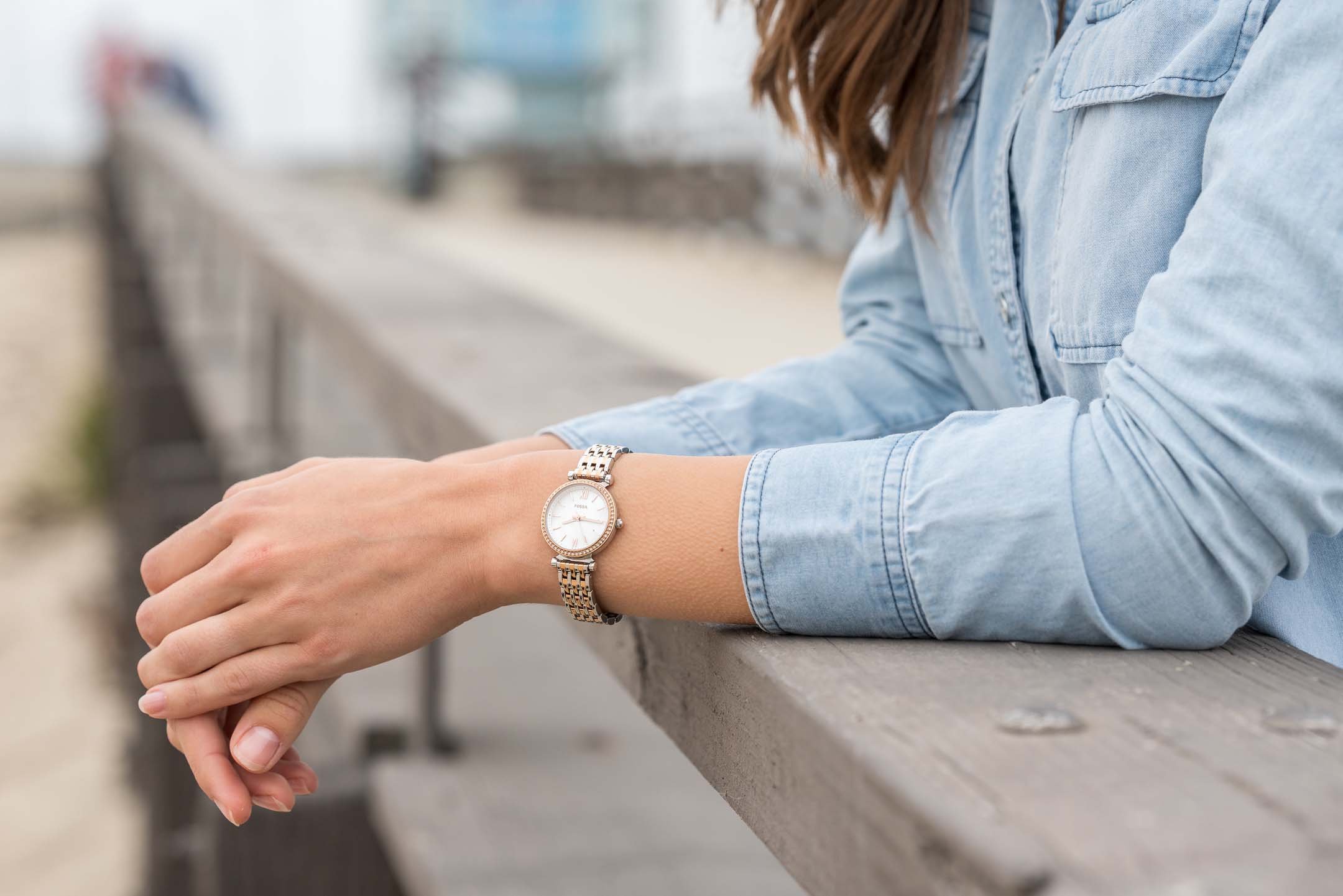 Woman wearing gold Fossil watch while leaning on the Venice Beach Pier