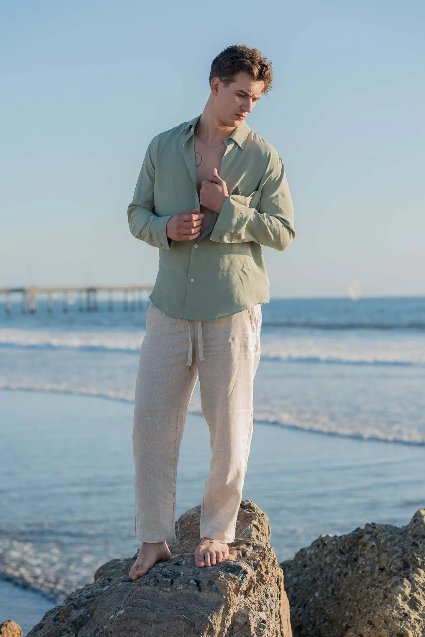 Los Angeles editorial fashion model posing on the rocks with resort wear at Venice Beach