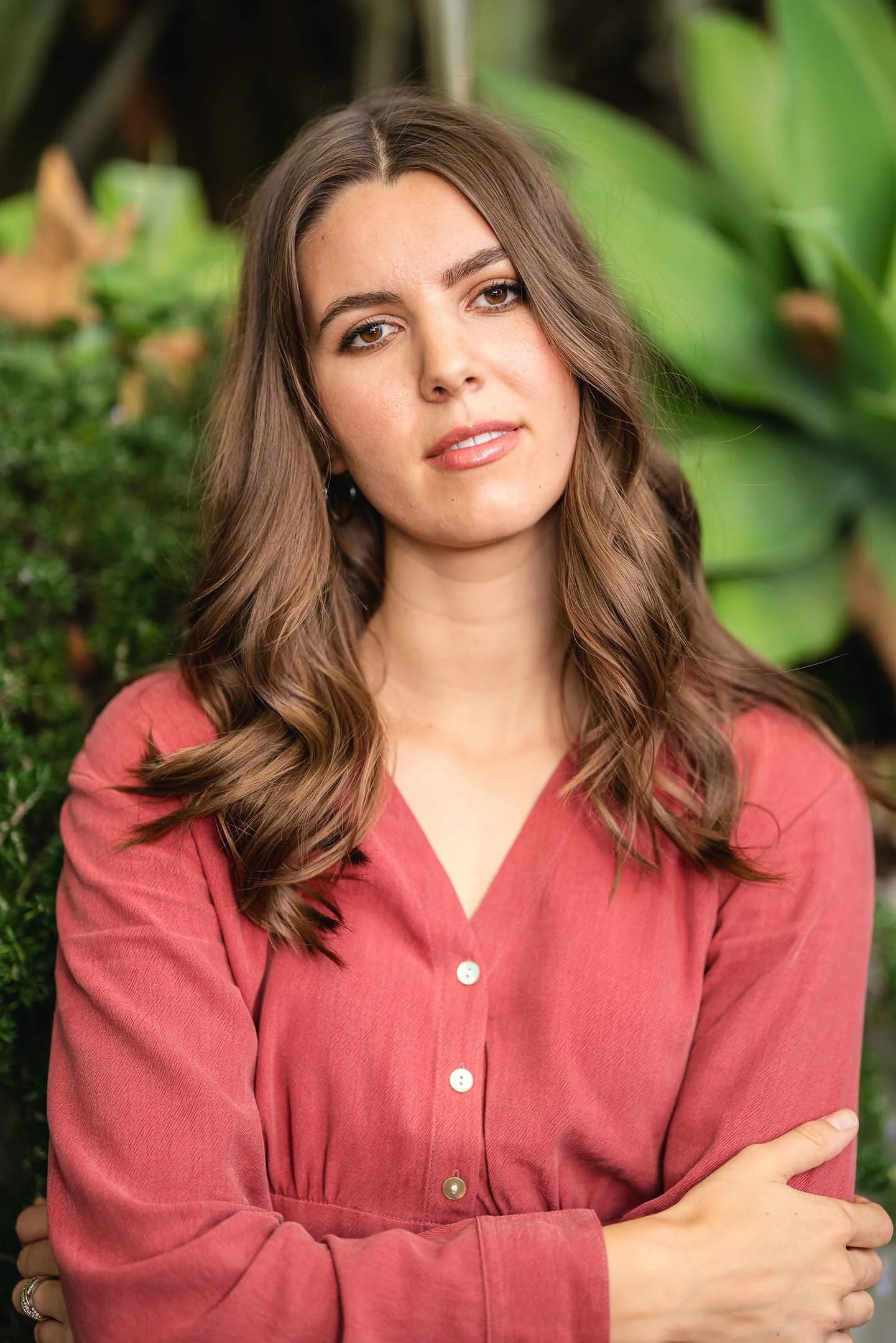 Woman posing with red shirt behind plants
