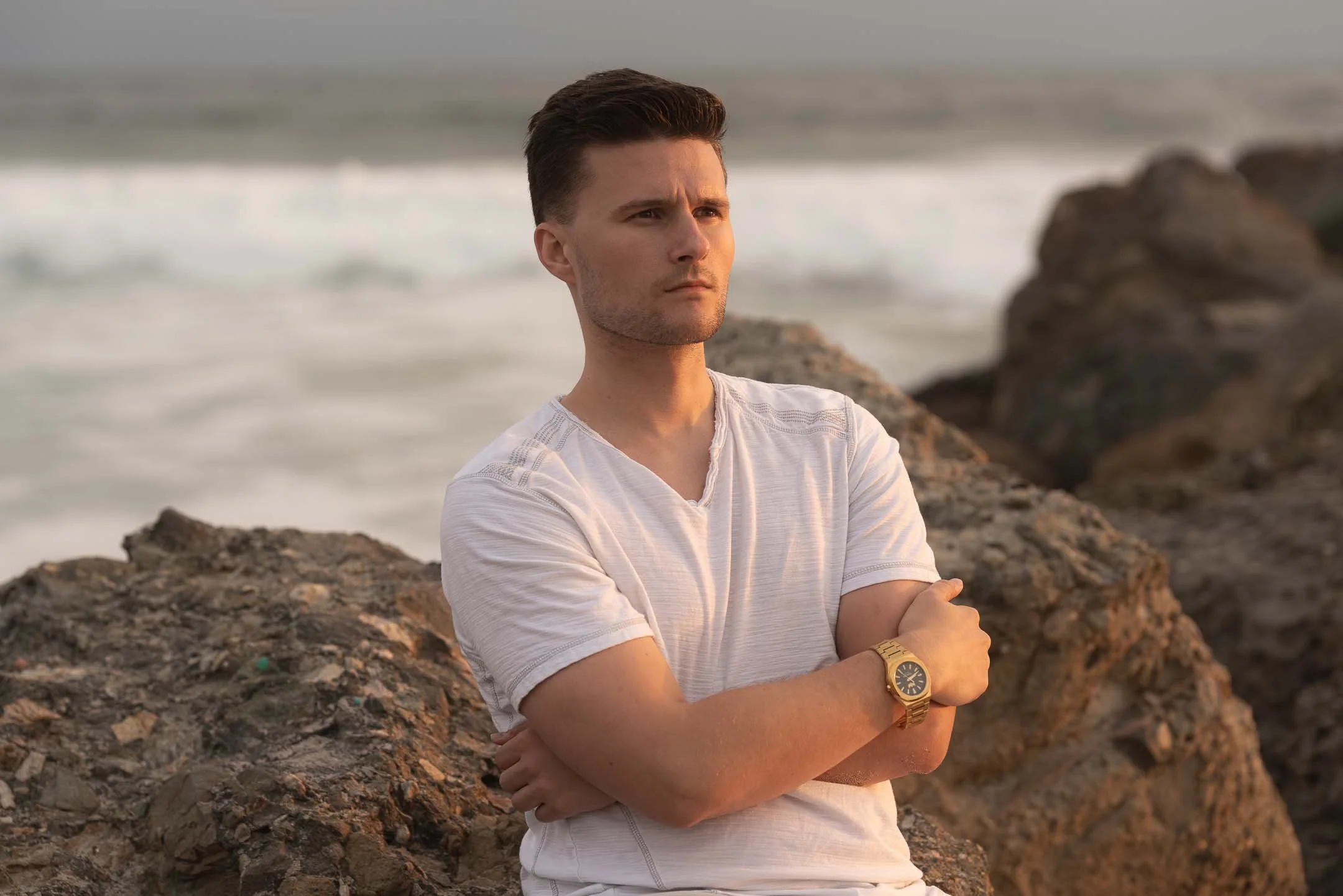 Los Angeles lifestyle model posing on rocks with gold watch at Venice Beach at sunset