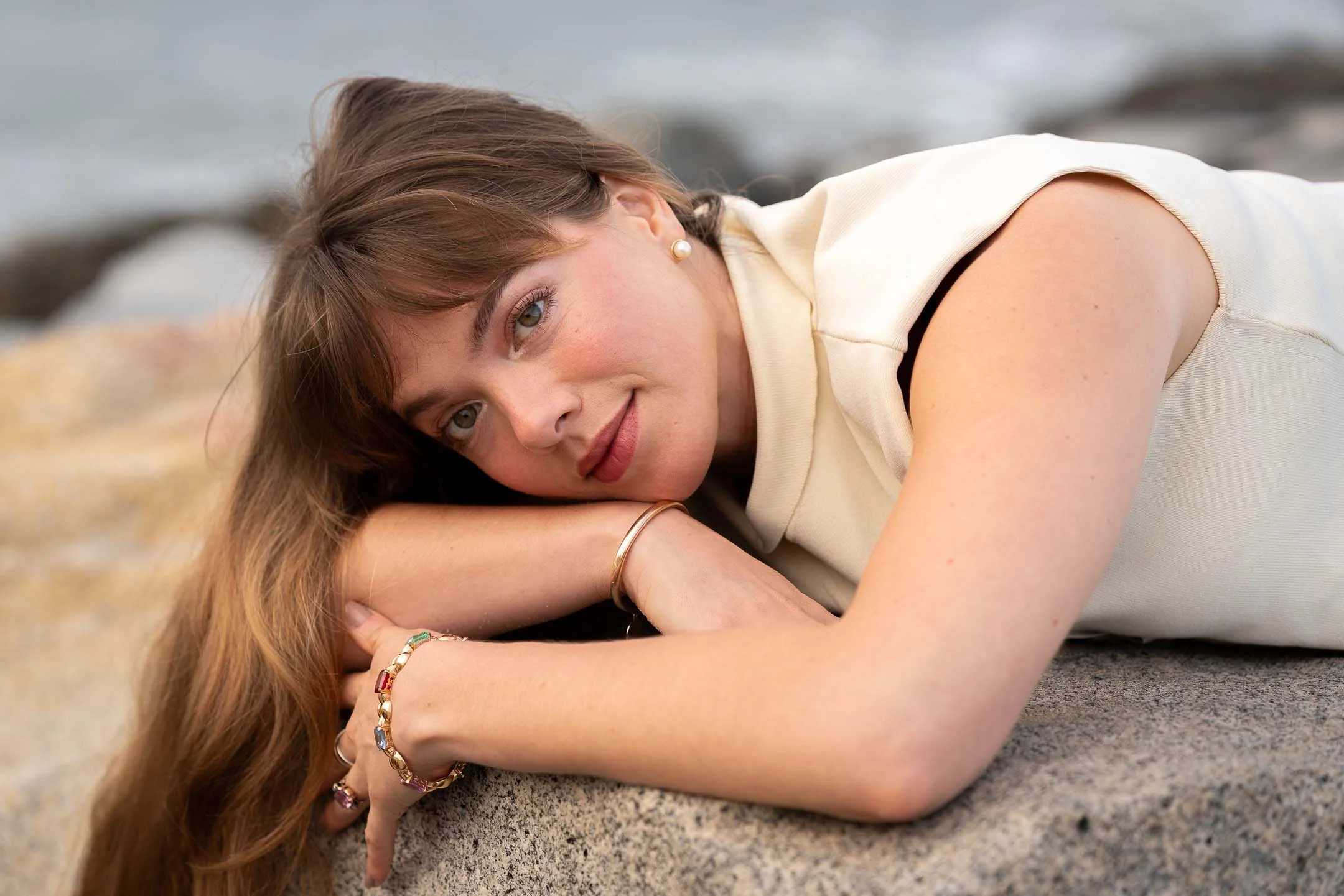 Model lying on the rocks at the beach wearing jewelry