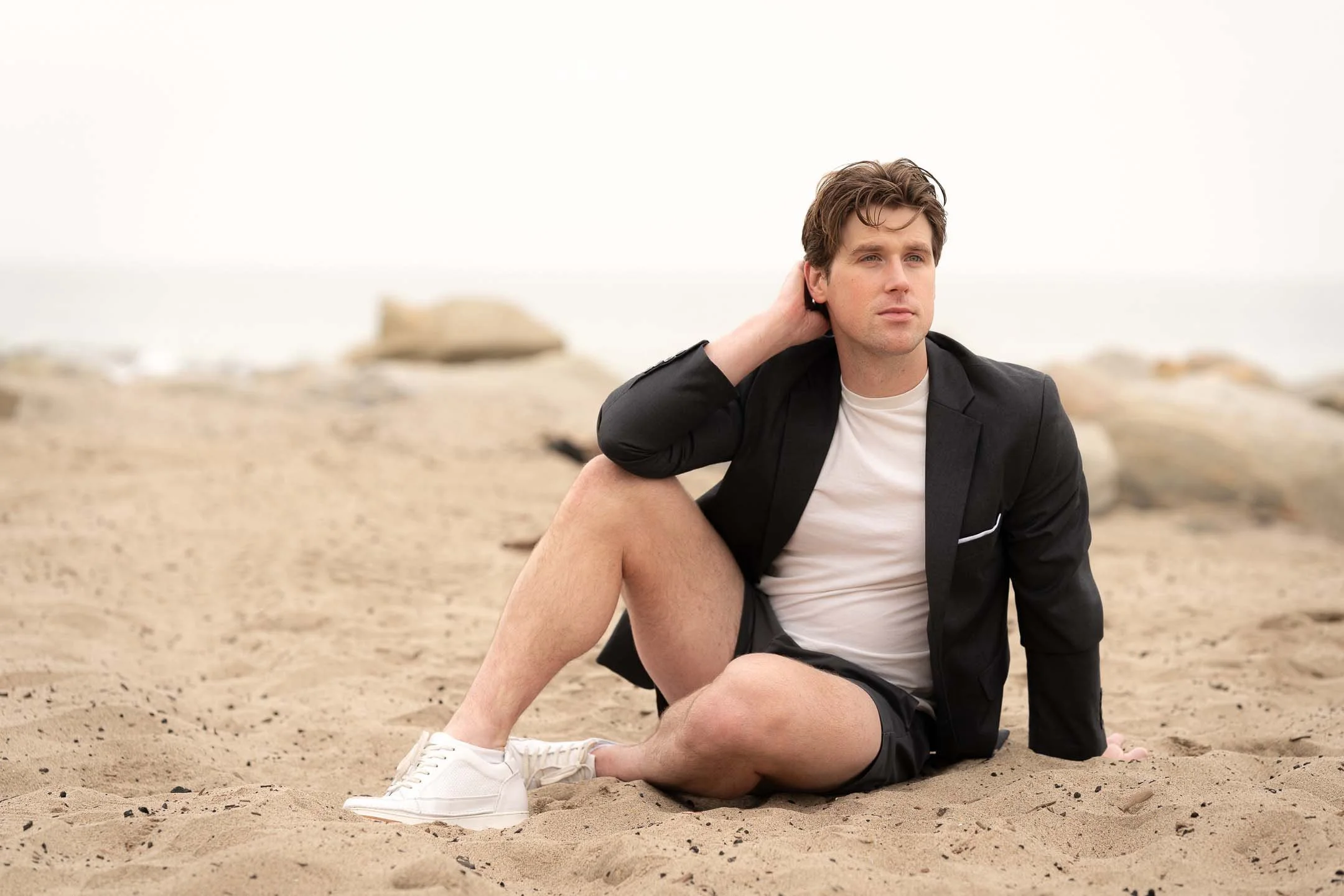 Male model posing and sitting on the beach in Santa Monica, Los Angeles