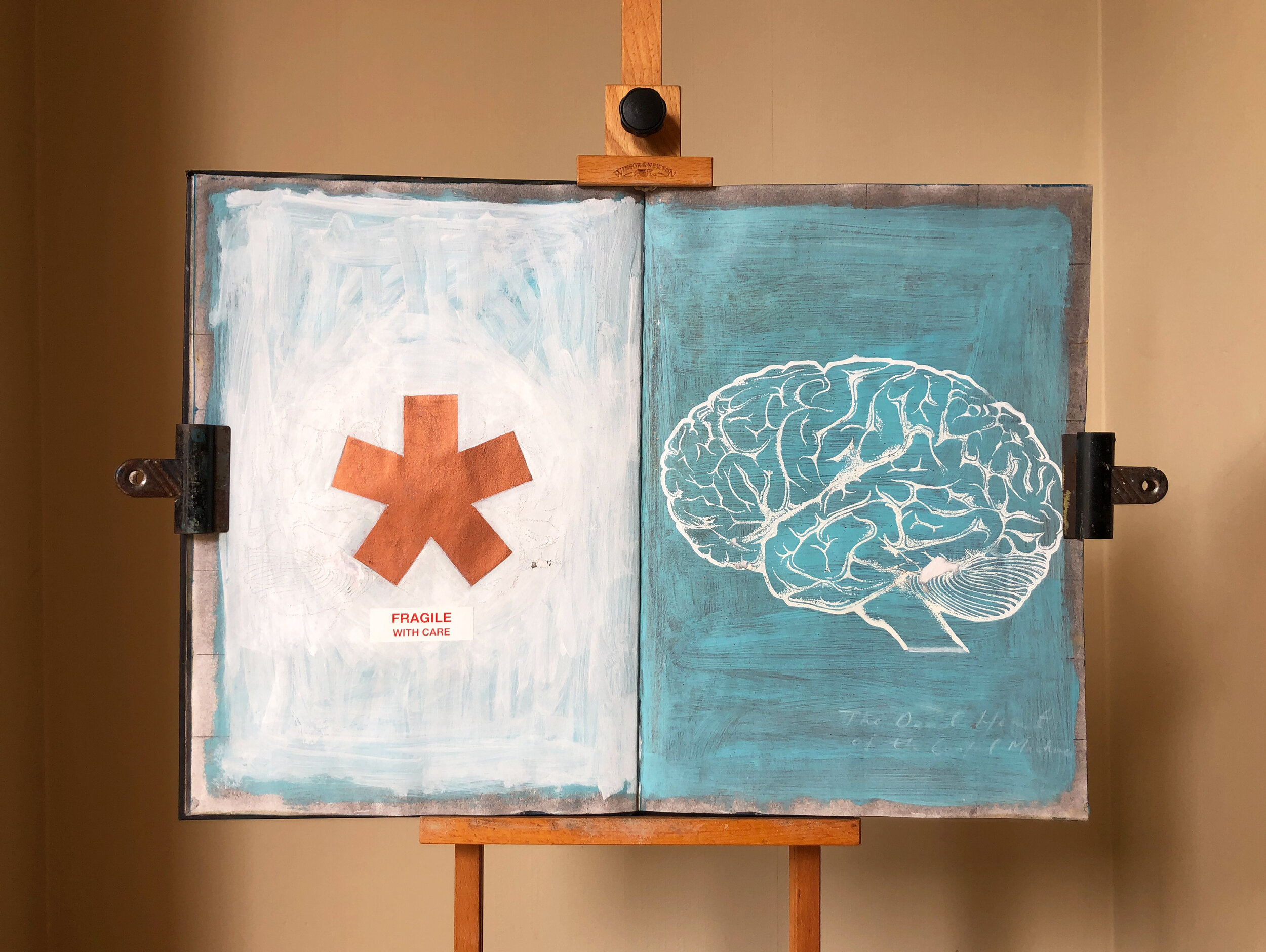 A sketchbook page. The left side has a white background with a large brown asterisk and a sticker that says 'Fragile with Care.' The right side features a blue-green background with a white outline drawing of a brain.