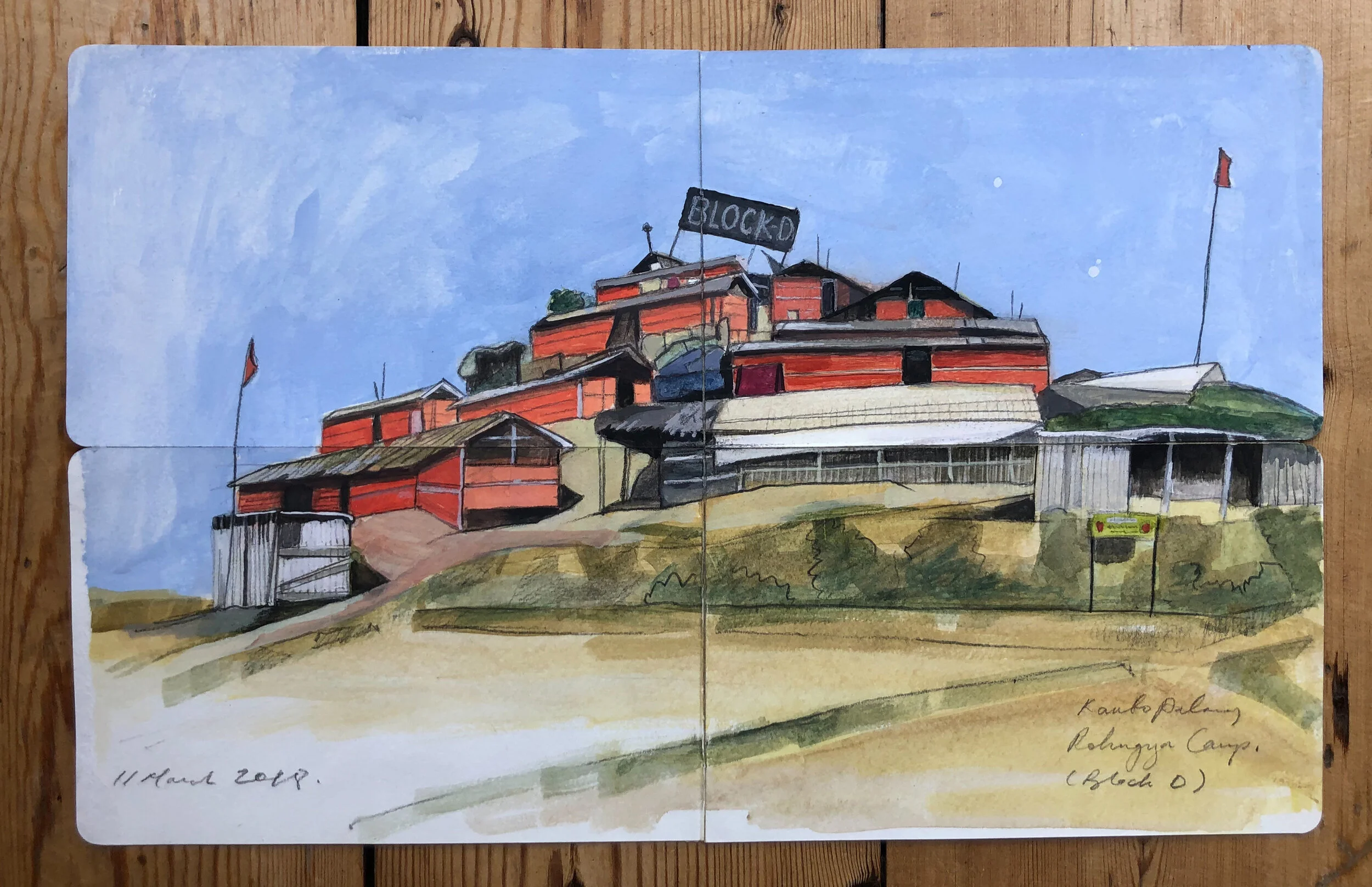 Watercolor painting of a hillside village with multiple red and gray buildings under a blue sky. The village has a sign that says 'BLOCKO' and flags on some structures. The painting is labeled as from 2018 and references Rabungya Camp at the bottom right.
