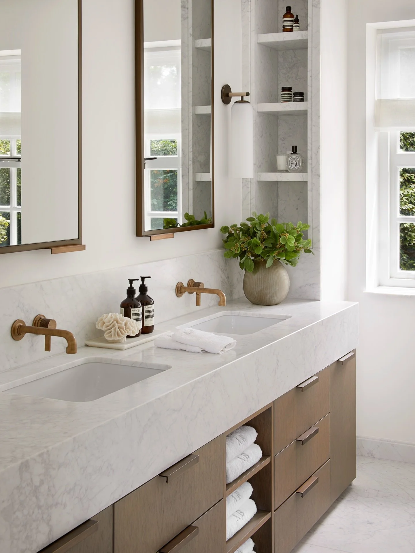 Step into an oasis-like sanctuary: the primary ensuite at our North London family home. A soft glow washes over the marble vanity. Integrated storage sits discreetly behind mirrored cabinets, with additional shelving and vanity drawers. Wishing every