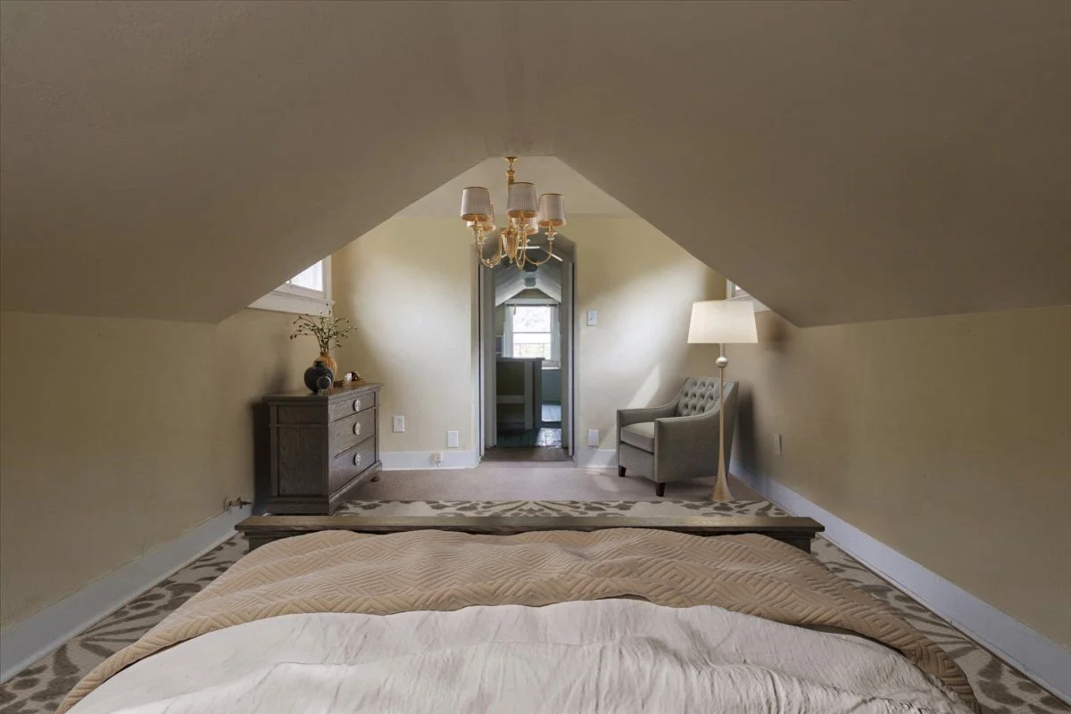 View of a cozy bedroom with sloped ceilings, a chandelier, a gray dresser with a plant, a beige armchair with a floor lamp, and a doorway leading to a bathroom or closet.