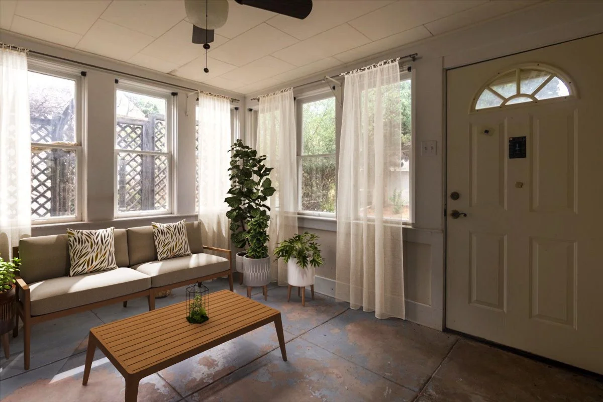 Sunlit living room with large windows, sheer curtains, a beige sofa with patterned pillows, multiple potted plants, a wooden coffee table, and a ceiling fan.