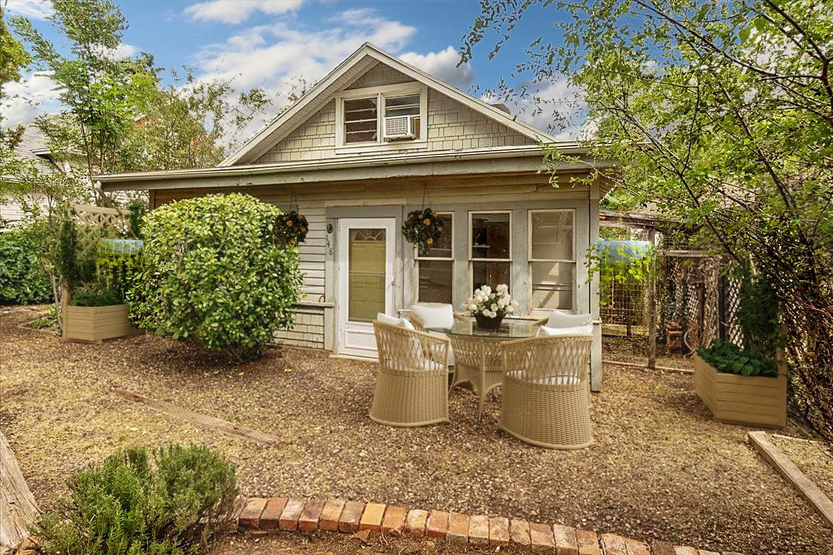 Cozy backyard with a small house, outdoor table, and chairs.