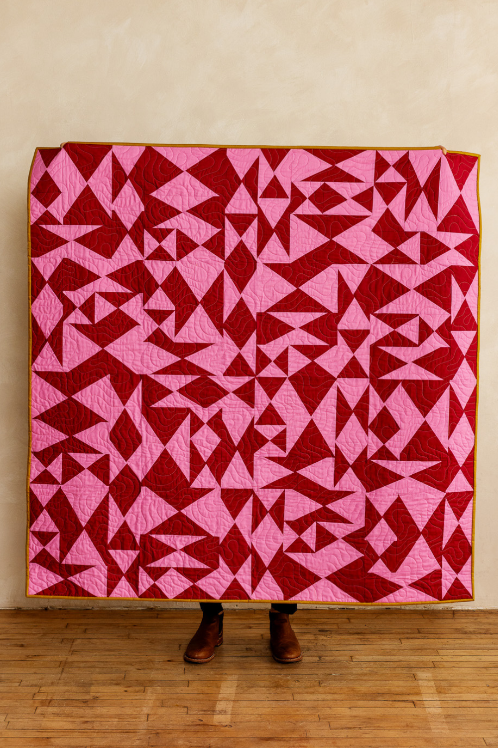 An improv patchwork quilt made up of a mix of quarter-rectangle-triangles in red and pink.