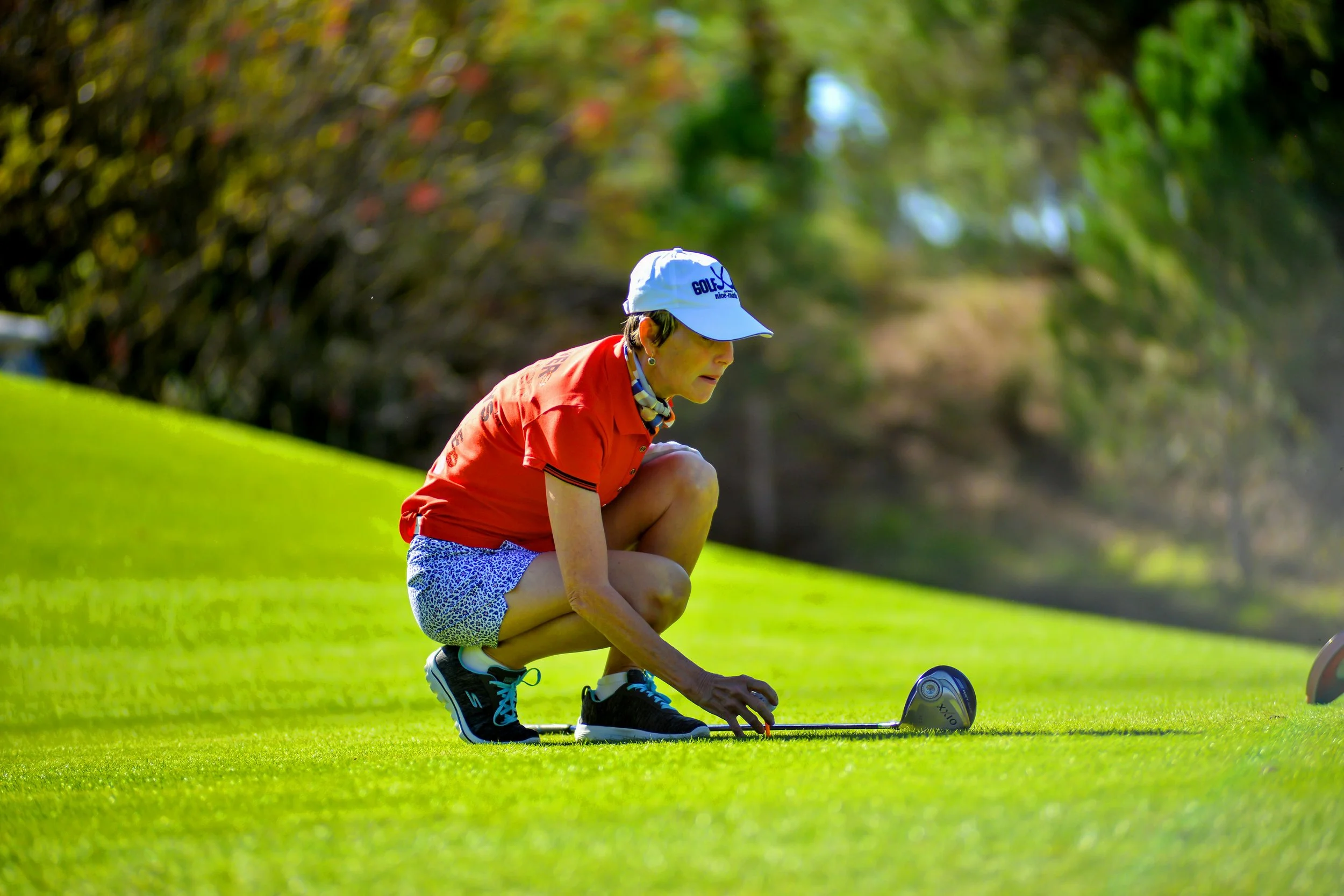 Adult female golfer bends down on the green