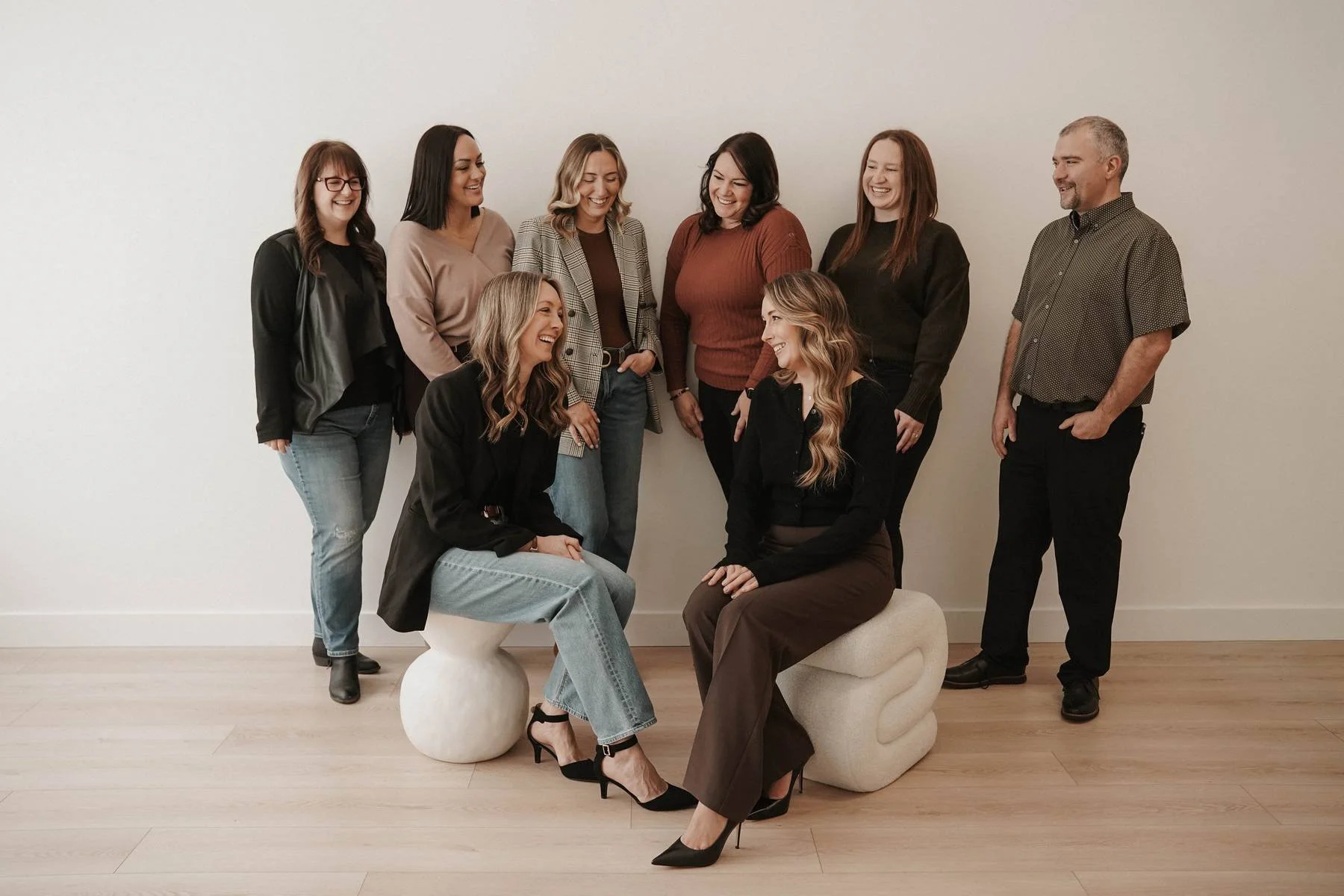 A team of online CBT therapists dressed in business wear or business casual smiling at each other.
