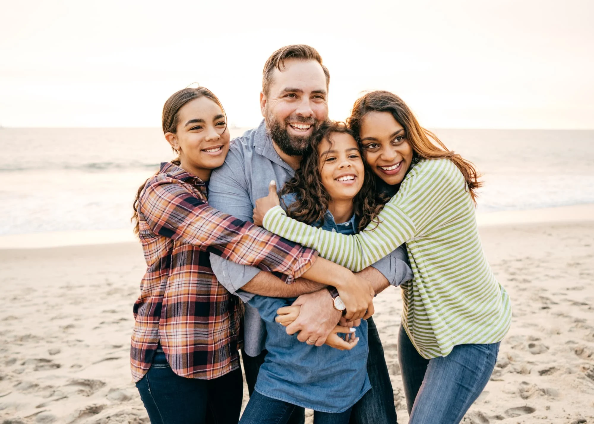 Family of four smiling with a beach in the background