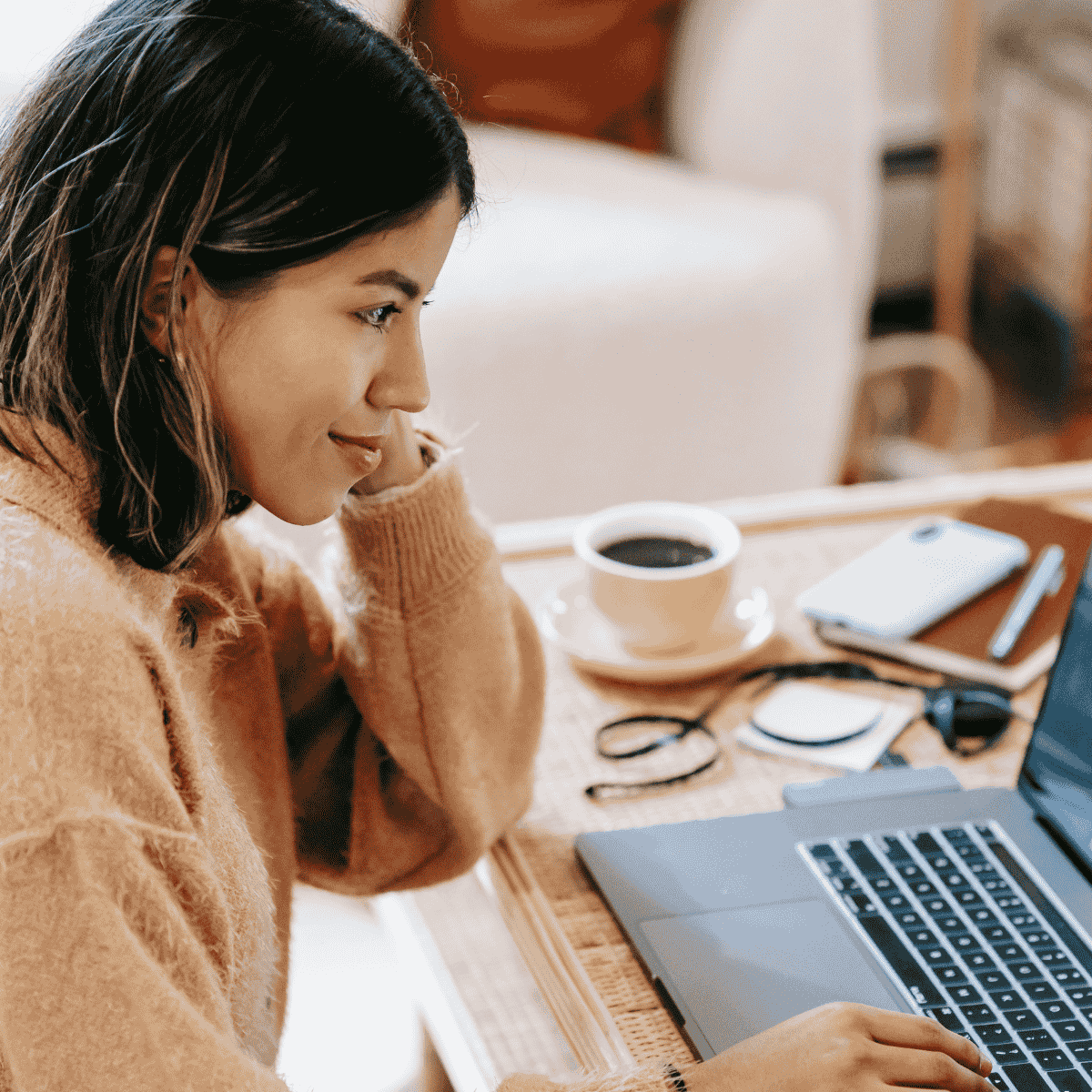 Woman sitting at her desk with laptop and coffee.