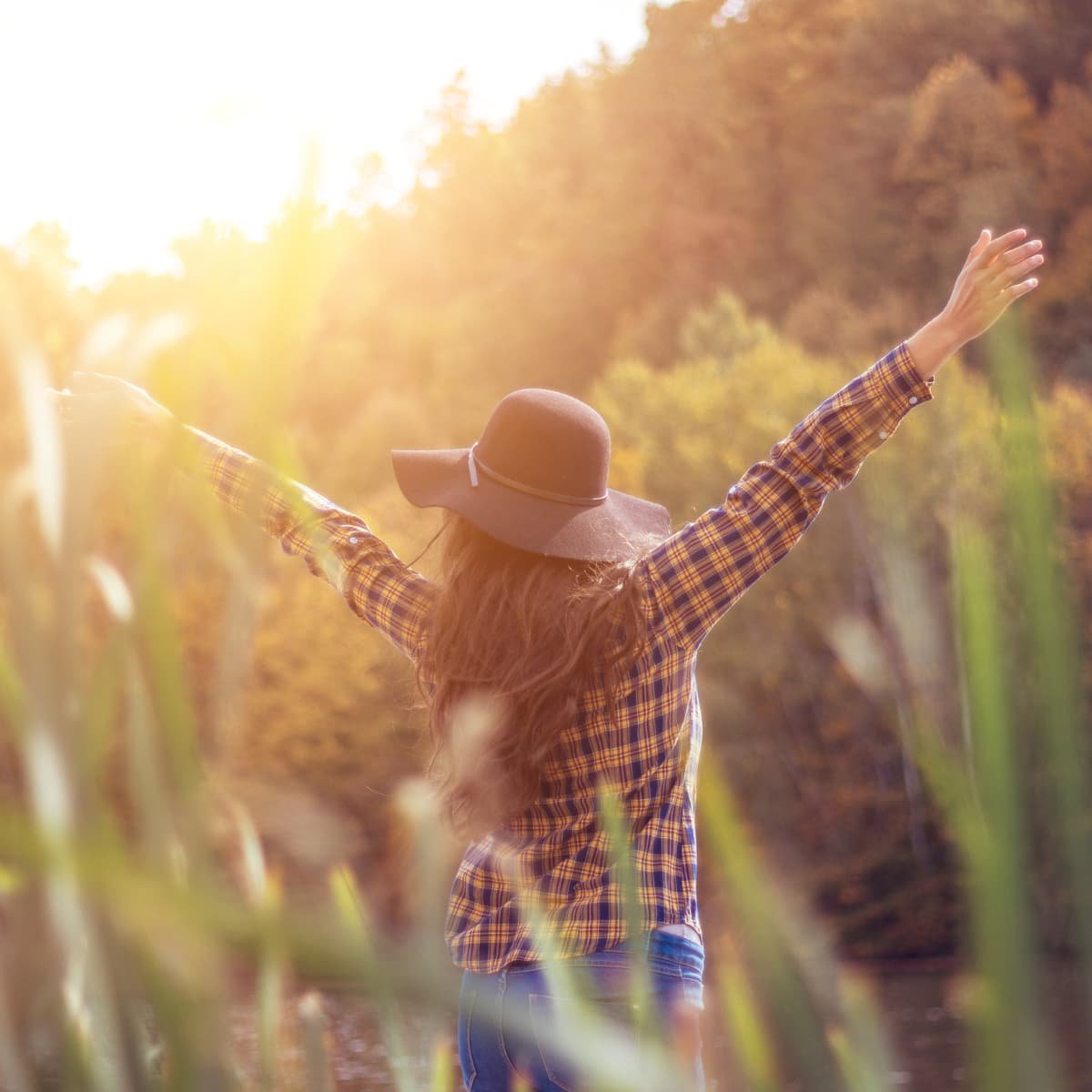 Woman in a field with her. hands up.