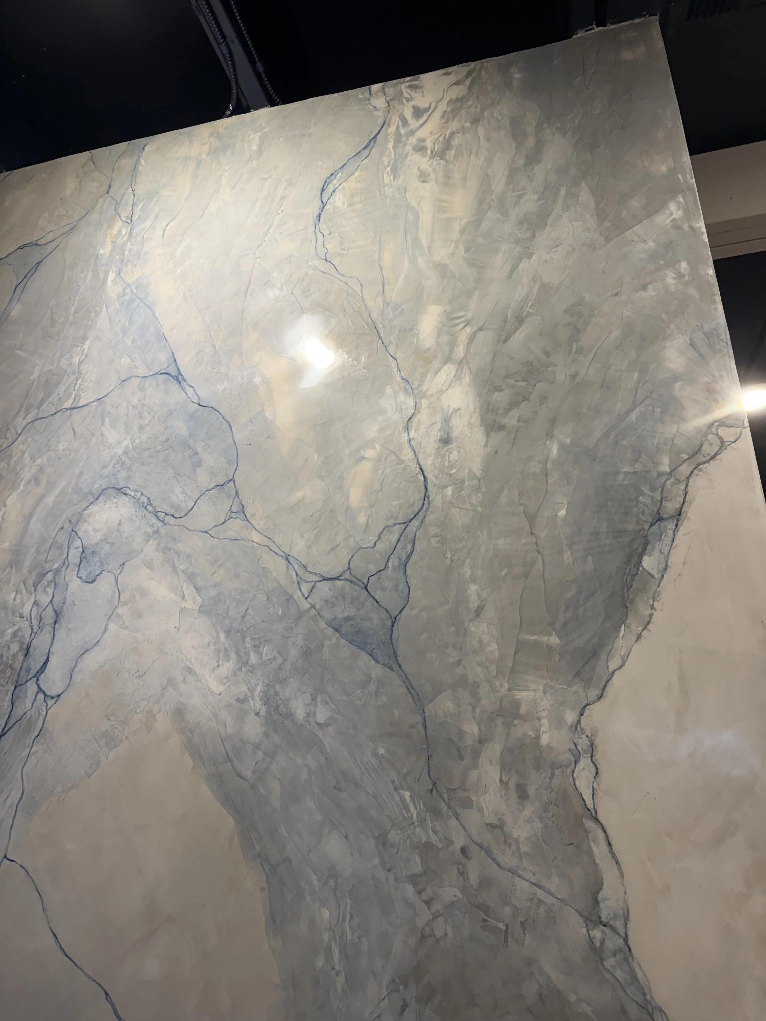 Close-up of a marble wall with gray and white veining and blue streaked veins.
