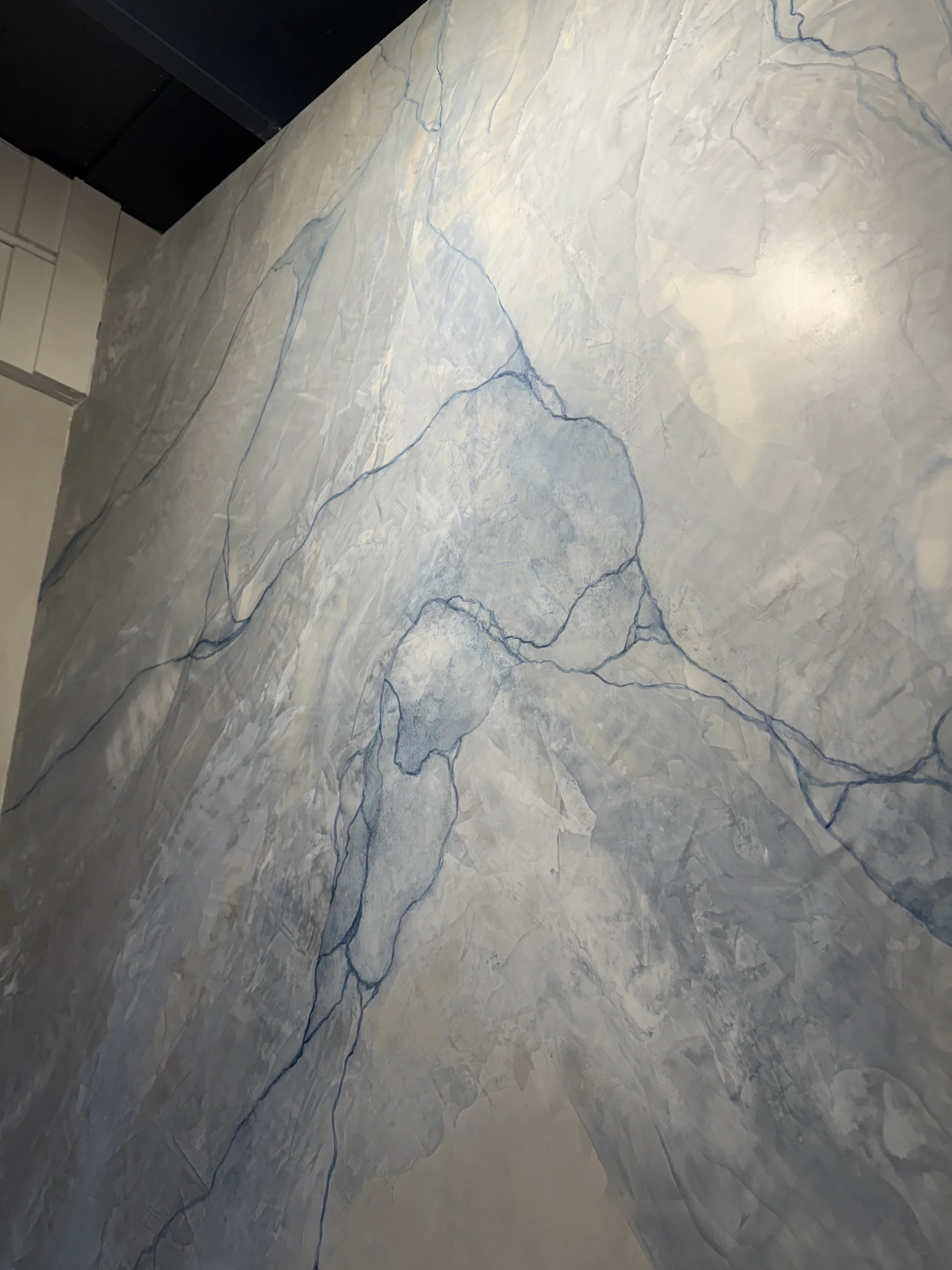 Close-up of a light-colored marble wall with dark blue veining.