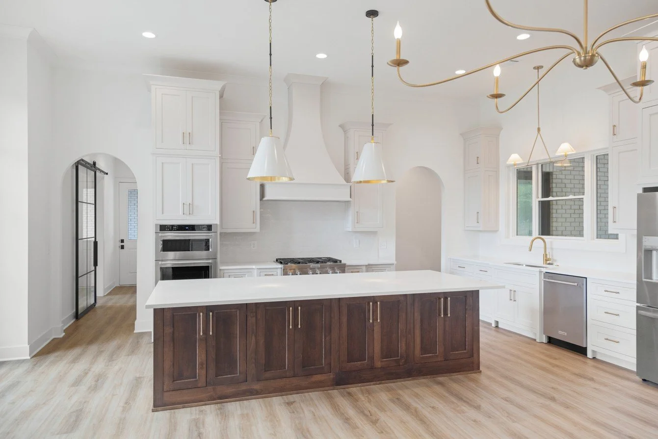 Custom kitchen in the Connelly home in Peachtree City featuring white cabinetry, a dark wood island, brass lighting and arched architectural details.