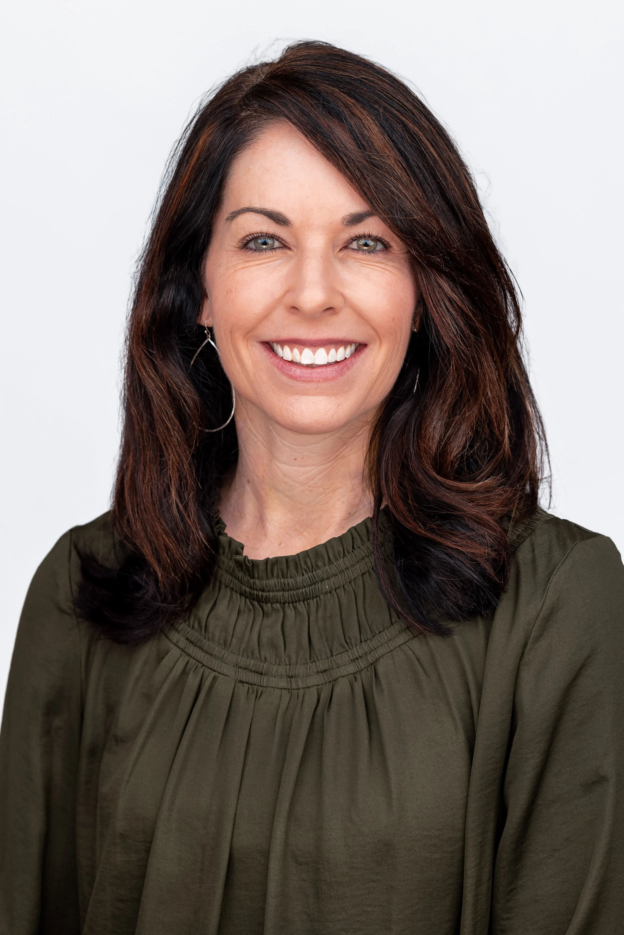 Dark haired woman smiling in a dark green blouse.