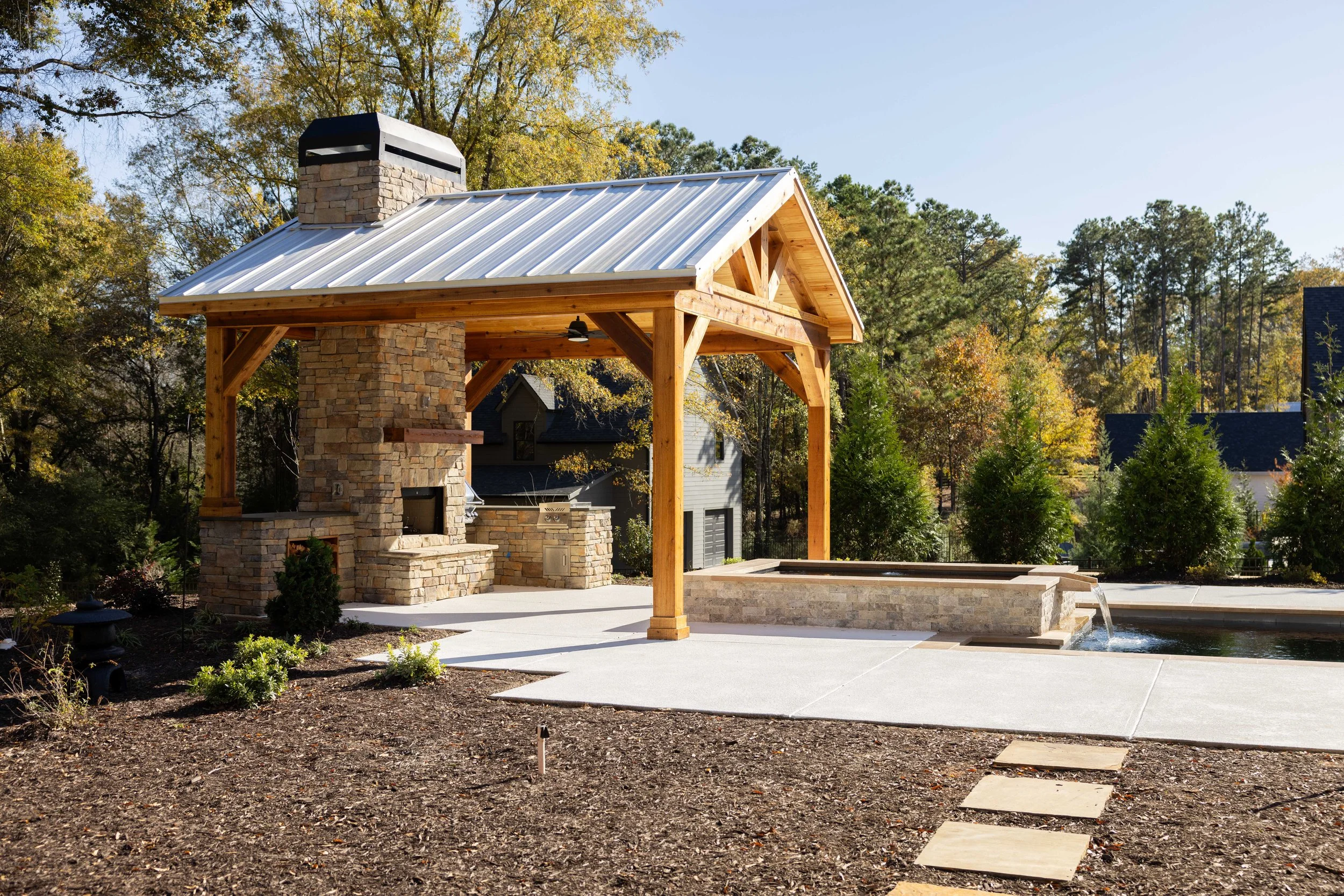 Covered outdoor living area with stone fireplace and pool at the Robinson home in Senoia, Georgia