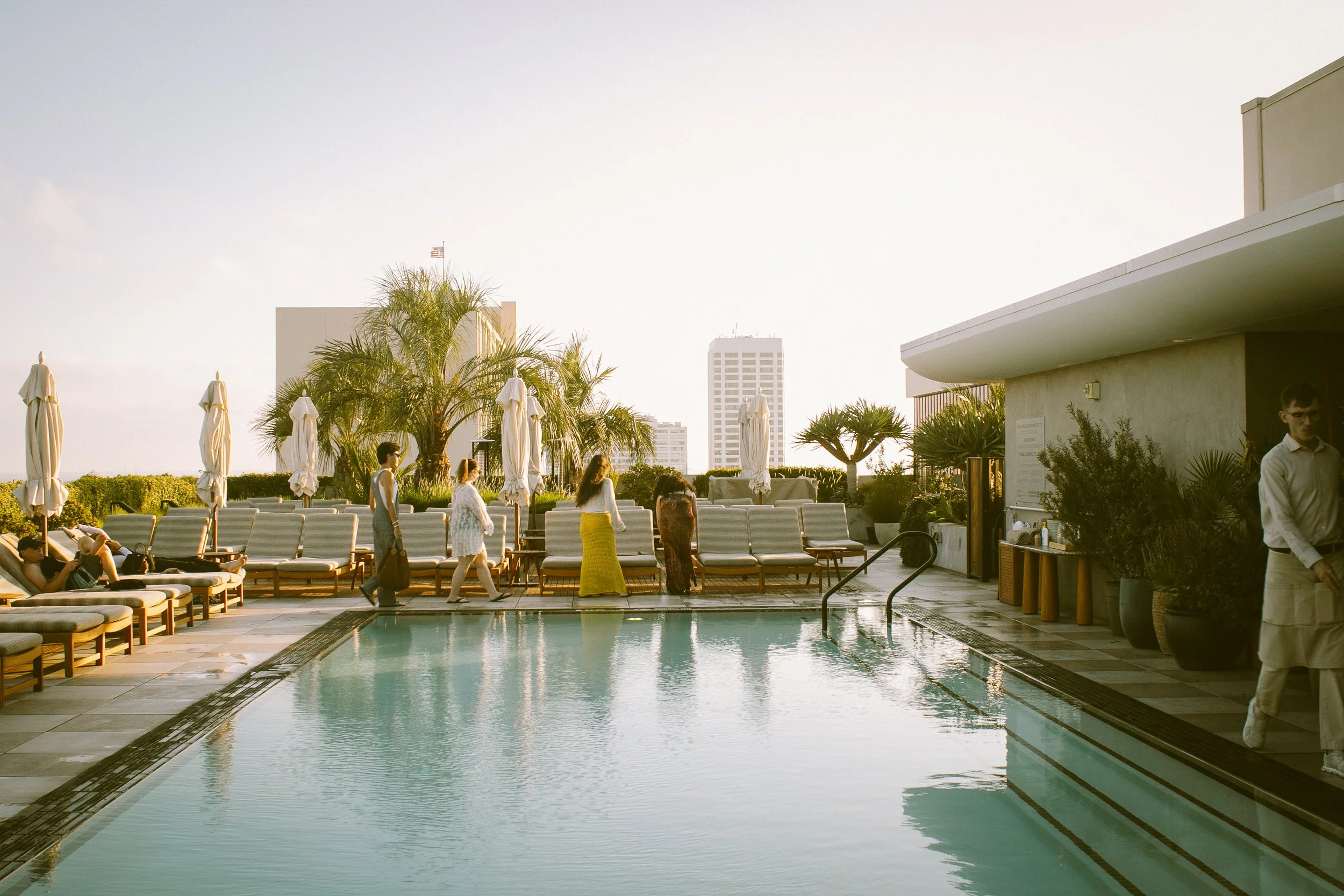 Slim Aarons style photography at the Santa Monica Proper Hotel showing the skyline of Los Angeles at sunset over a pool