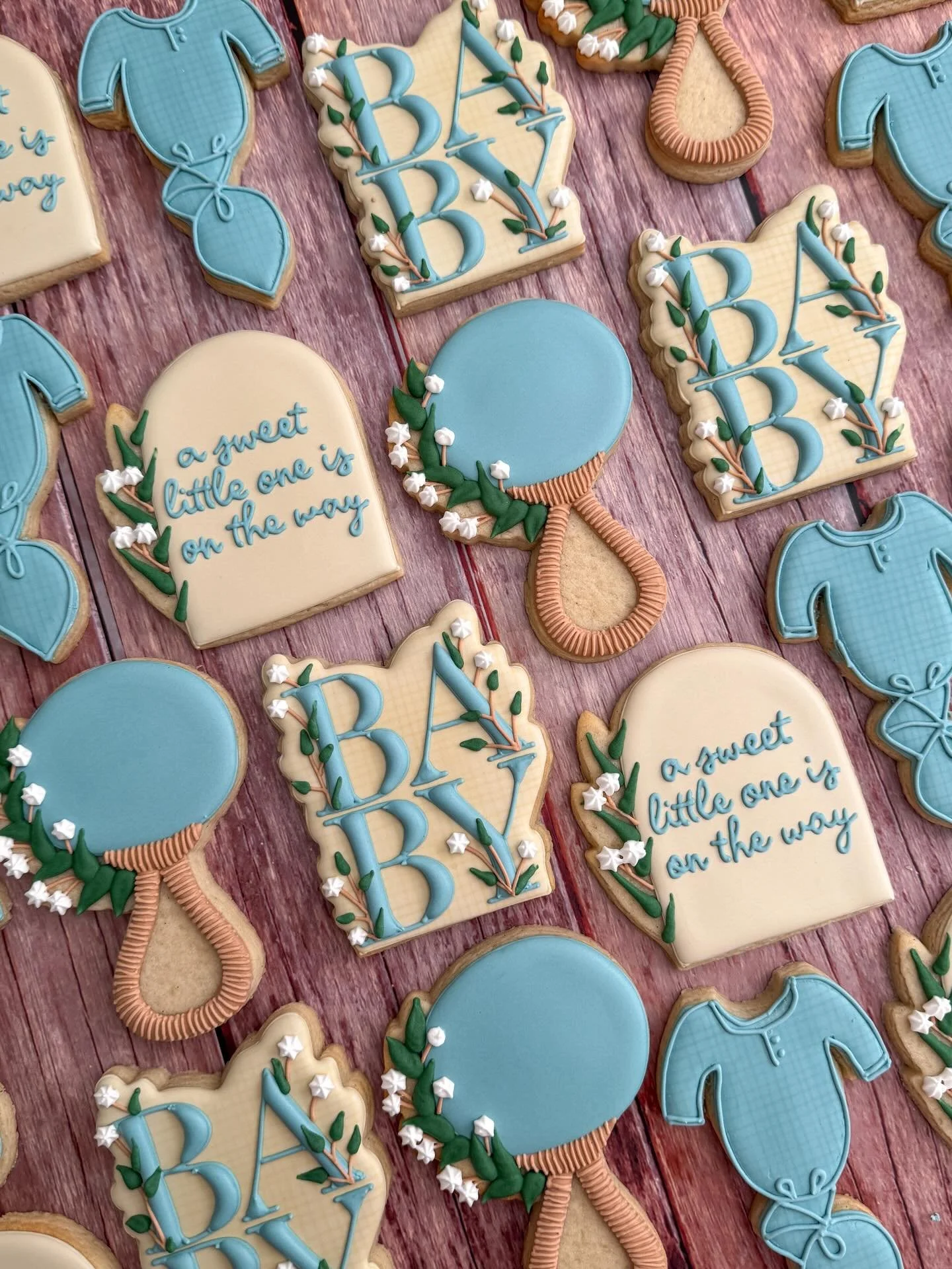 Baby blues 🩵
Custom sugar cookies in soft dusty blue featuring textured onesies, layered BABY monograms, rattles, and &ldquo;a sweet little one is on the way&rdquo; plaques for the sweetest baby shower celebration.

#tatestreats #babyshowercookies #