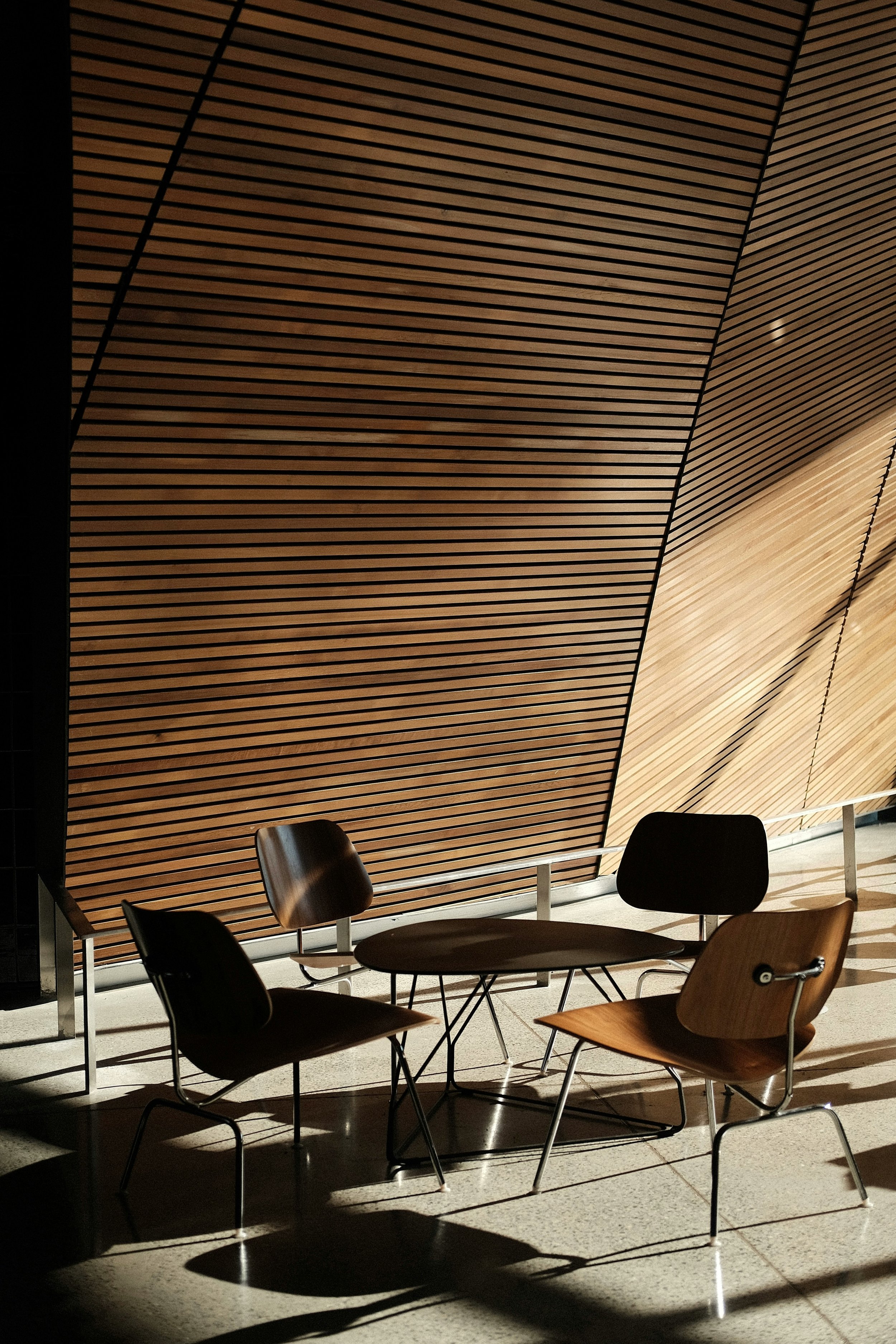 An empty table and chairs in front of a timber slatted wall