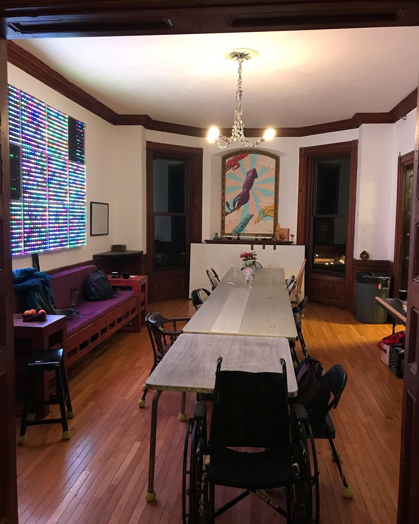 The dining room, empty, featuring tEpilepsy, our programmable LED board, our squid mural, and the chandelier made out of silverware