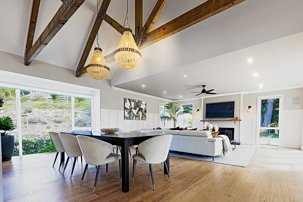 Dining room with exposed timber beams and kitchen beyond.