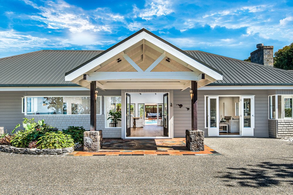 Renovated Sandspit house with a pale exterior and welcoming entrance.