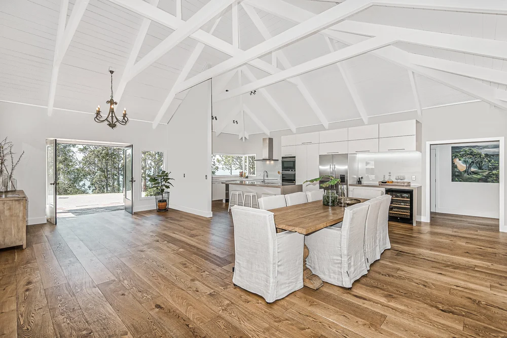 Open dining area with timber flooring and a white vaulted ceiling.
