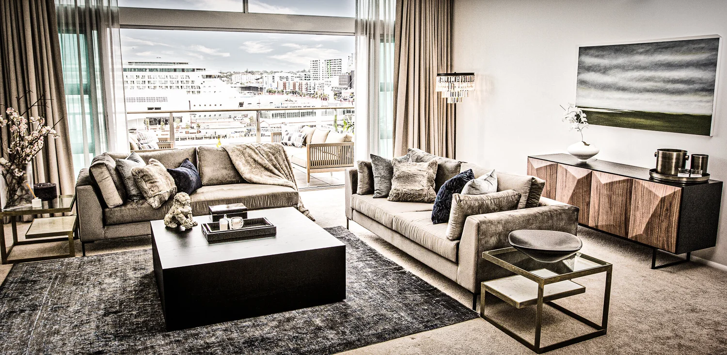 Grey sofas and layered rugs in the Hilton waterfront apartment, with balcony beyond.