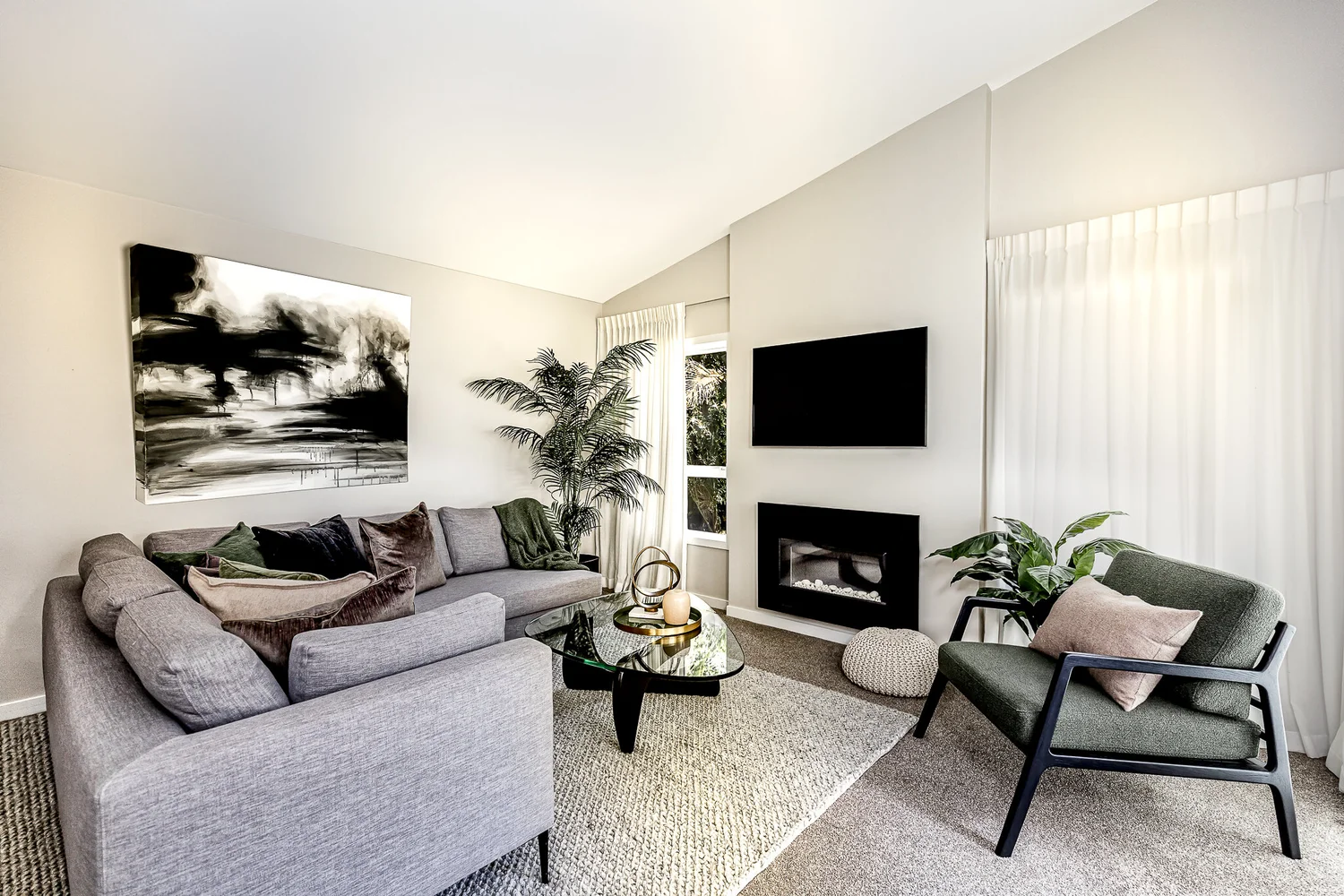 Grey corner sofa, green cushions and dark occasional chair in Kohimarama.