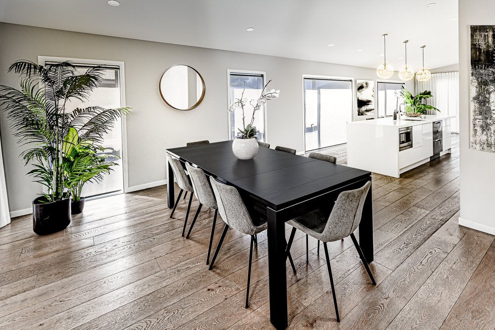 Dark dining table and chairs beneath a round wall mirror.