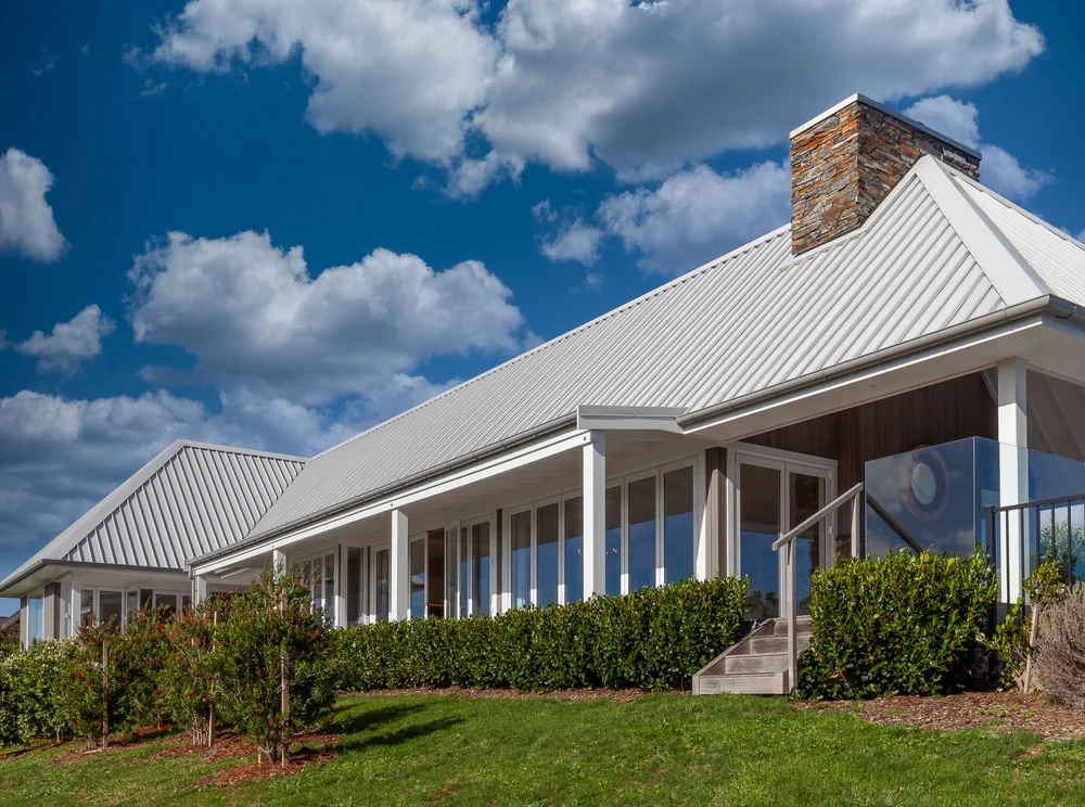 White country house with a pitched roof and garden in Matakana Hills.