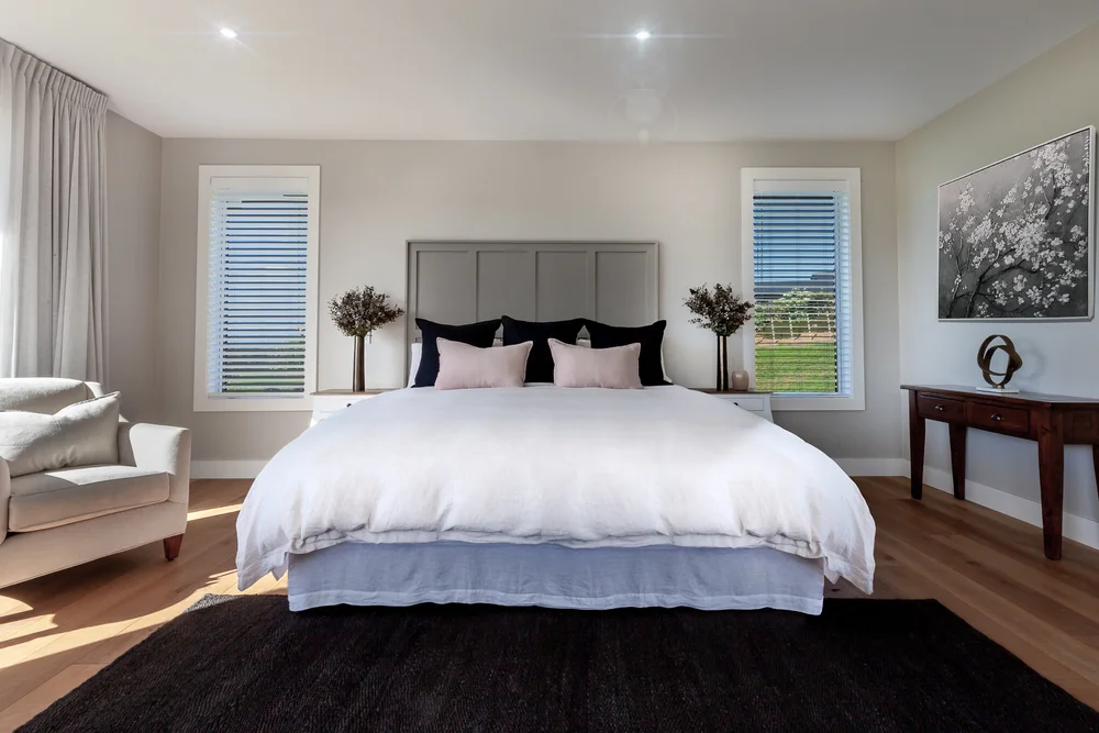 Bedroom with a panelled headboard and layered neutral bedding.
