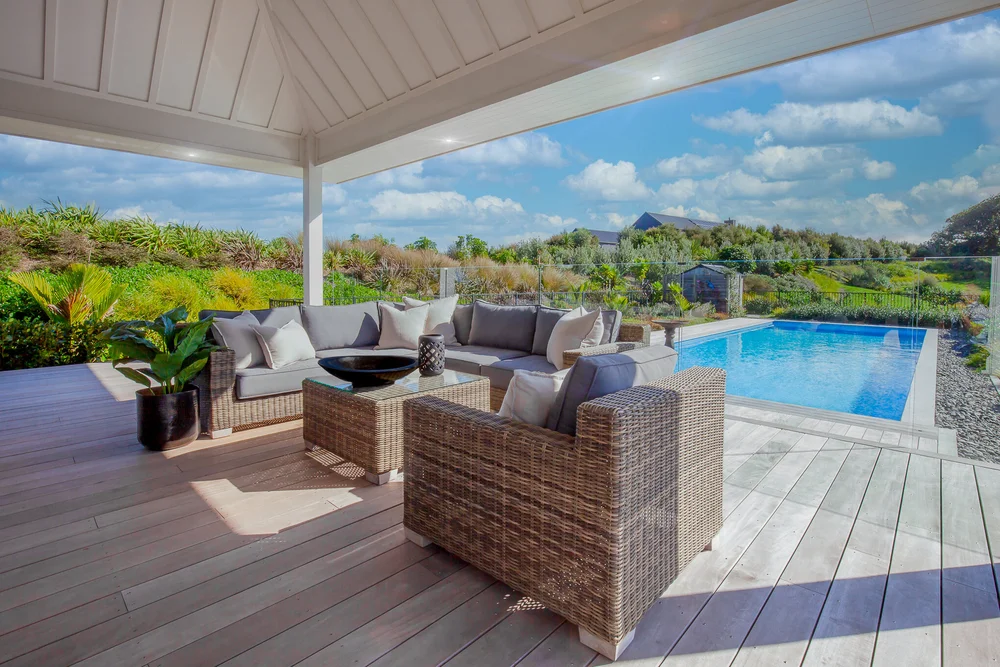 Covered terrace with woven outdoor seating beside the swimming pool.