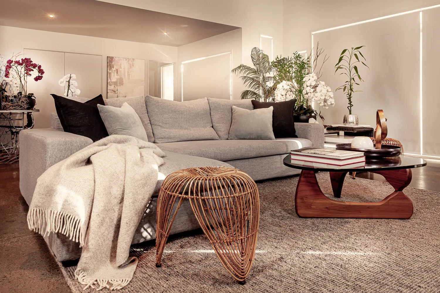 Omaha lounge with grey sofa, layered cushions and sculptural timber table.