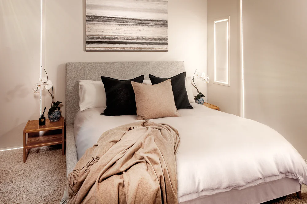 Omaha bedroom with neutral bedding, dark cushions and wall art.