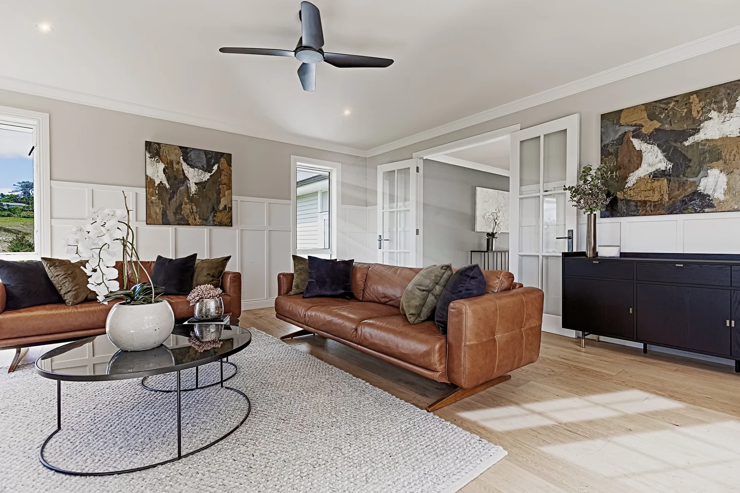 Camel leather sofas, earthy cushions and artwork in the Coatesville living room.
