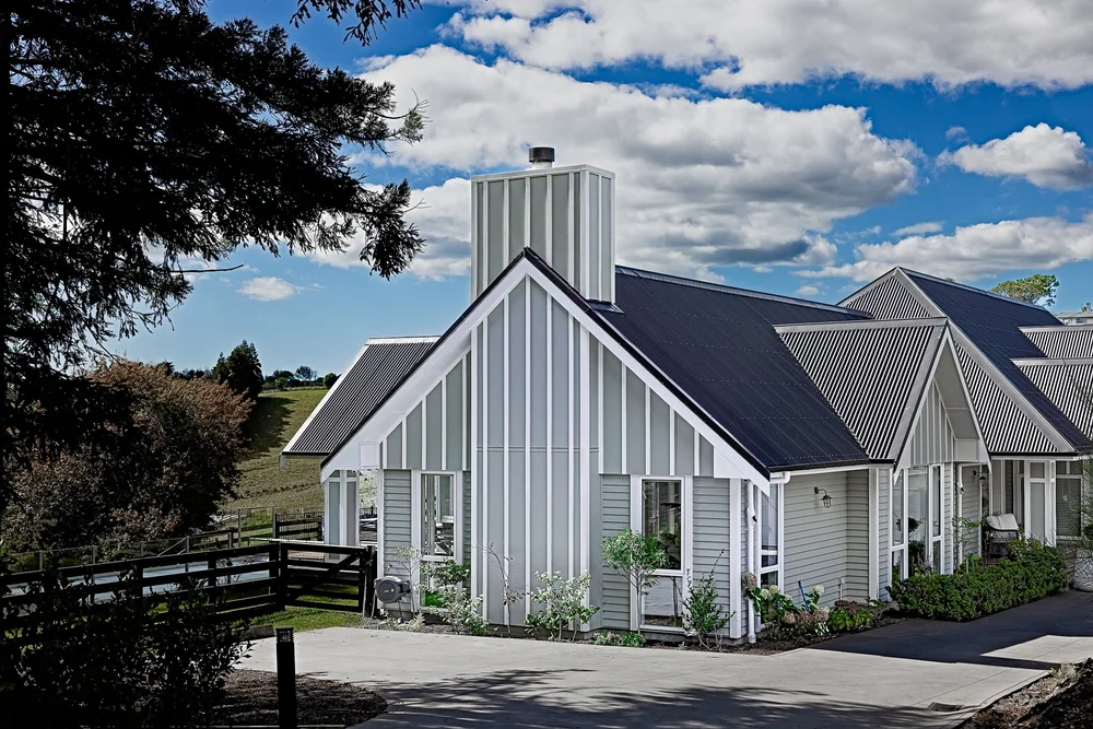 Pale grey Coatesville house surrounded by gardens.