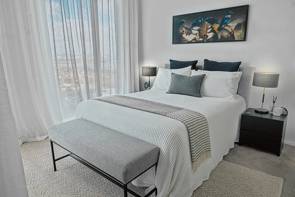 Takapuna bedroom with white linen, black accent cushions and artwork.