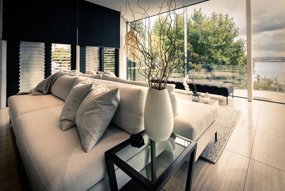 Pale sofa and cushions with a side table beside the window.