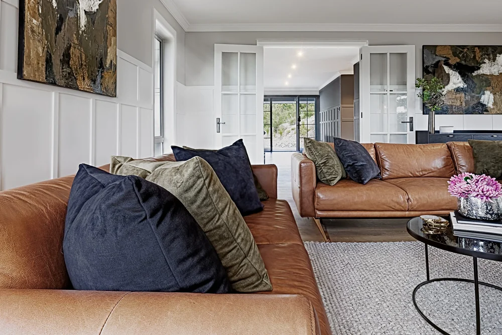 Detail of a leather sofa with patterned and textured cushions.