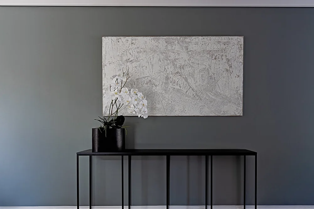 Console table with abstract artwork and faux orchids.