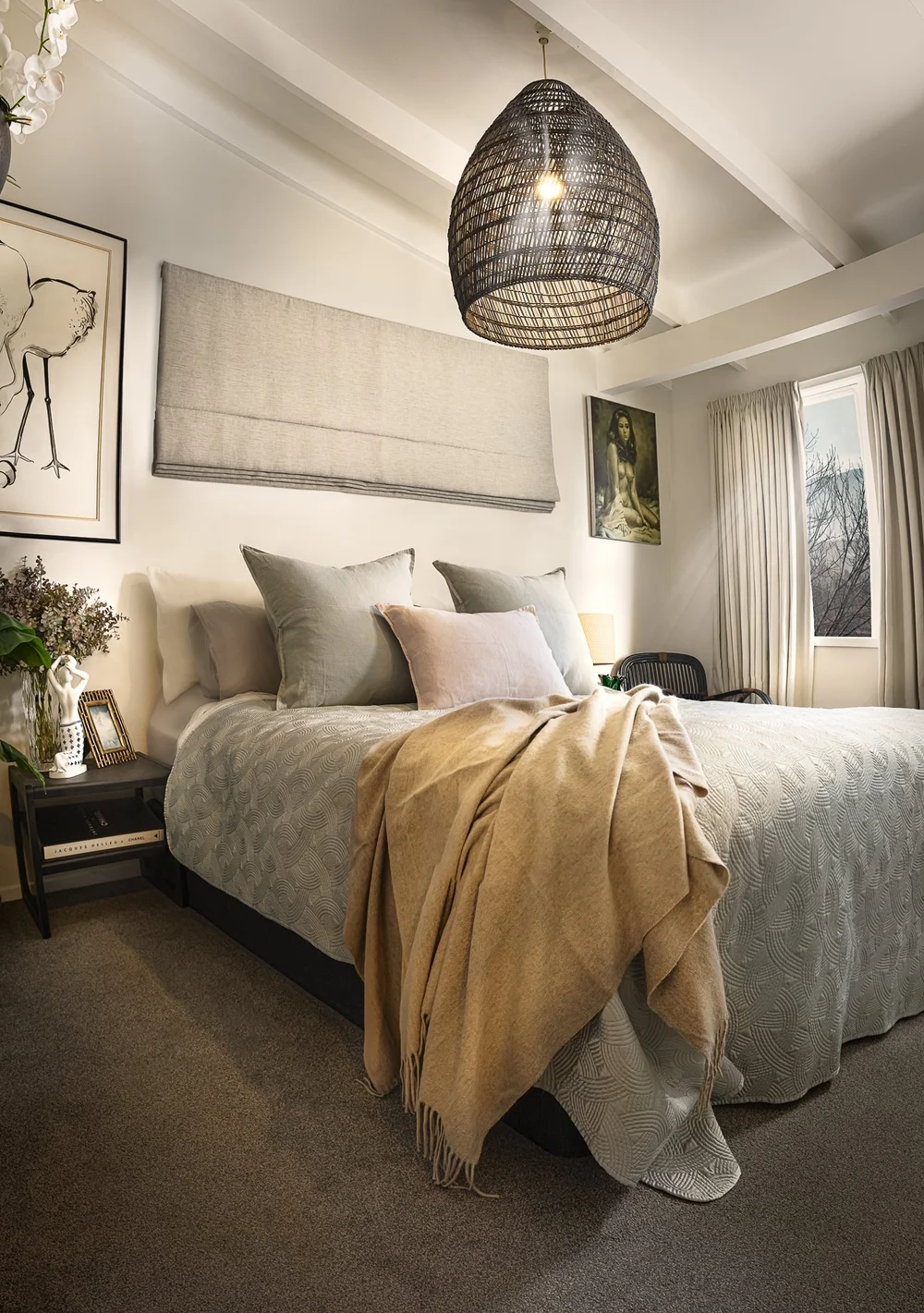 Mahurangi West bedroom with layered bedding and a woven pendant.