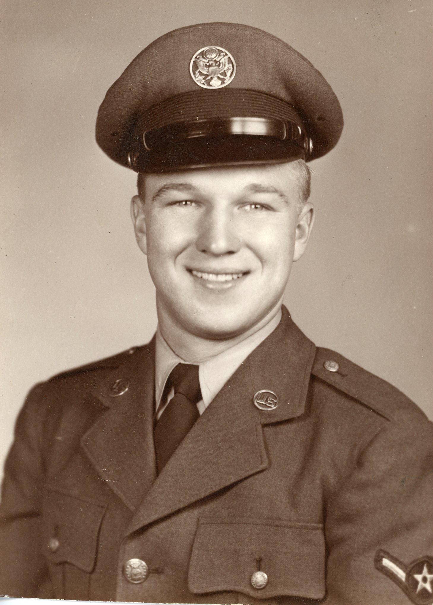 Vintage photo of a smiling man in a U.S. military uniform with a cap.