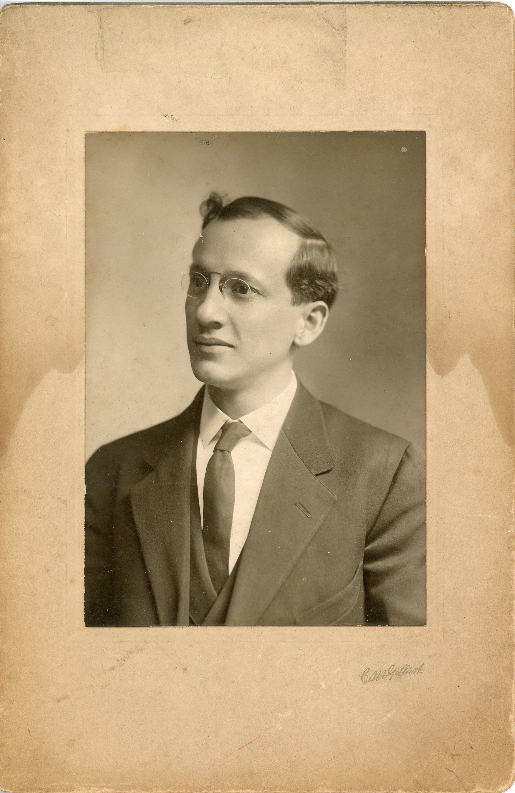 Vintage portrait of a man wearing glasses and a suit, early 20th century style.