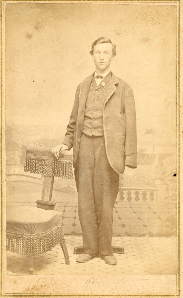 Vintage sepia photo of a man in a suit standing next to a chair