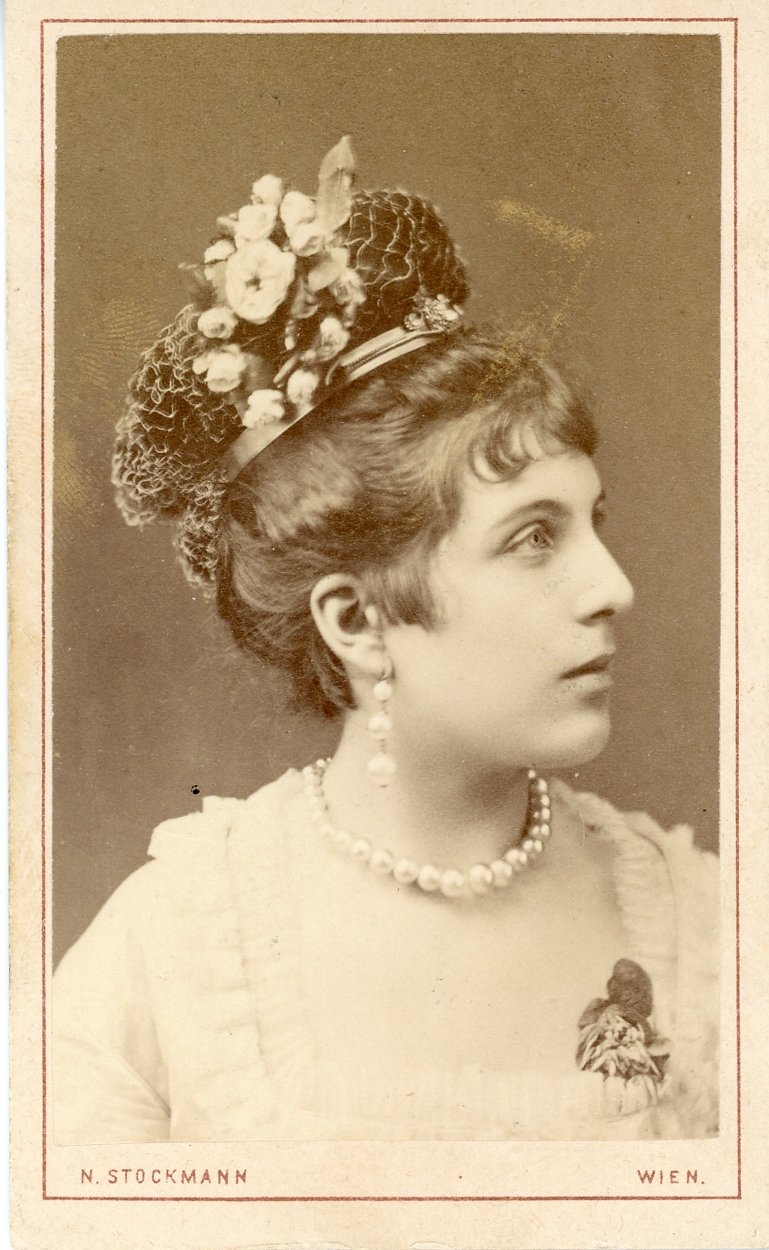 Vintage portrait of a woman in profile wearing a floral headdress and pearl necklace